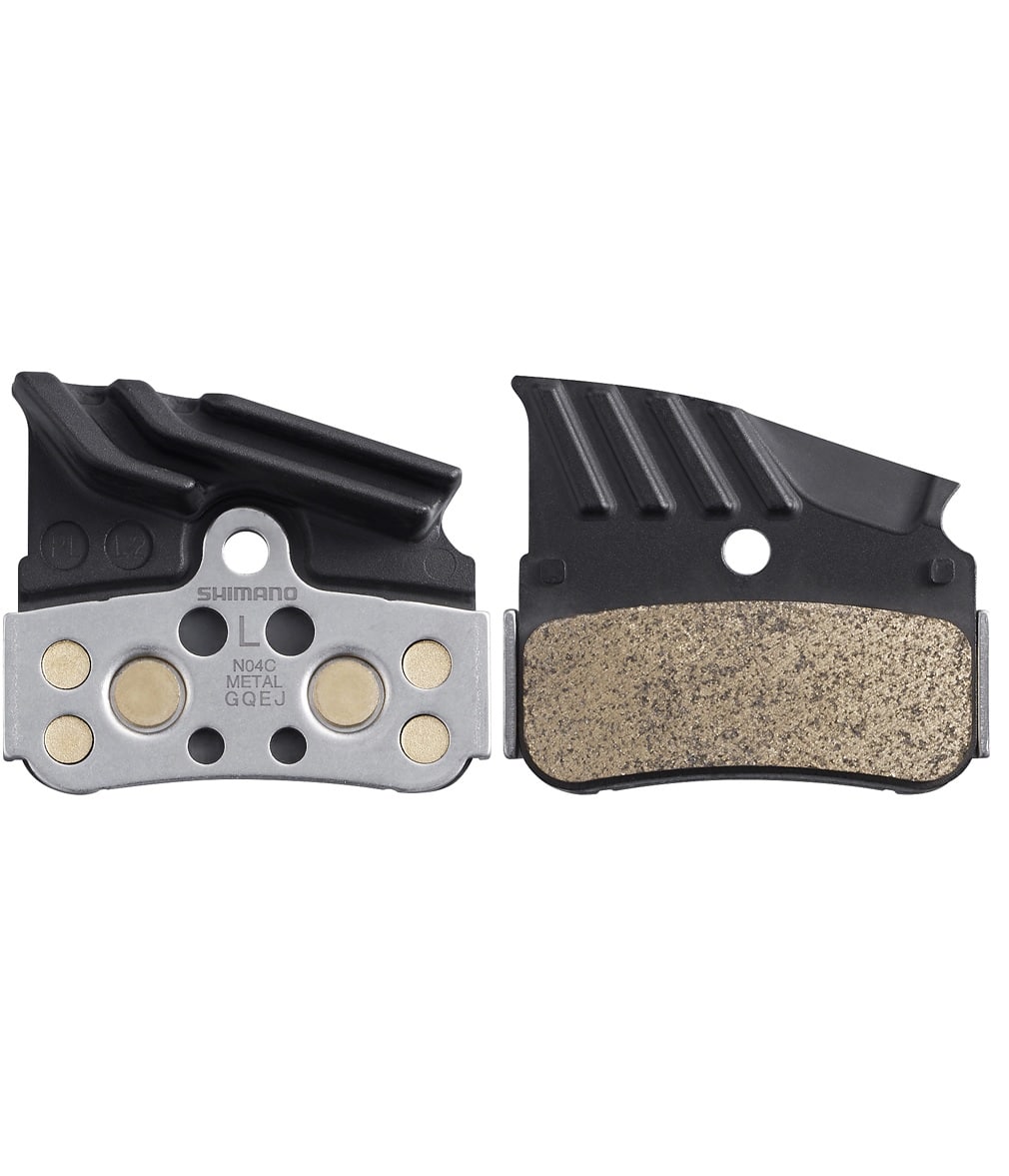 N04C-metall-BR-M9120.jpg Två Shimano skivbromsbelägg i metall för cyklar visas sida vid sida, där det ena visar stödplattan och det andra visar bromsytan i metall. Varje belägg har en svart övre del och en metallisk nedre del.