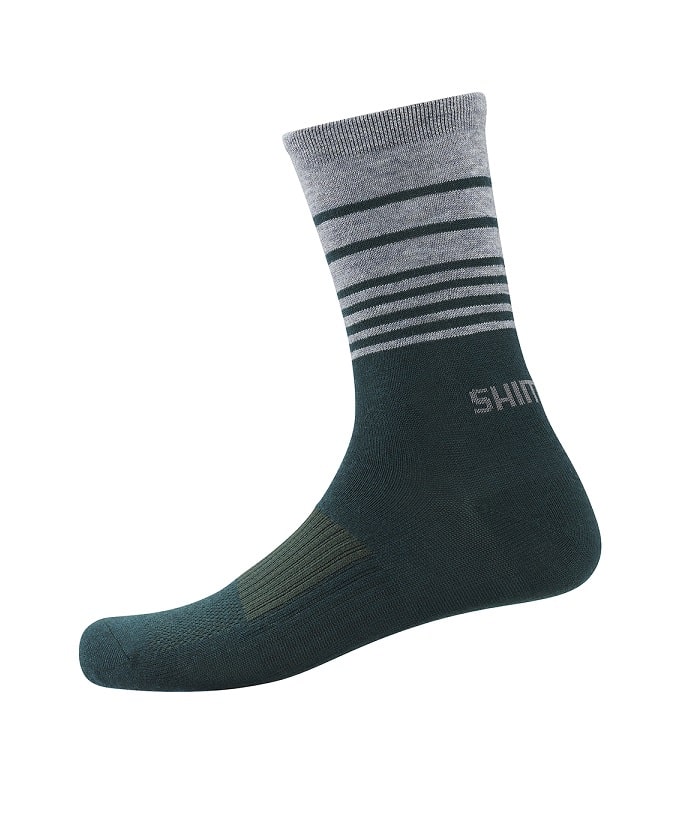 Original-Wool-Tall.jpg En enkelstrumpa med mörkgrön fot och häl, ljusgrå mudd och horisontella grå ränder runt vristen. Märkesnamnet "SHIM" syns nära vristen i ljusgrå text.