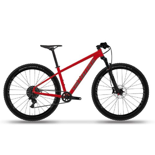 En röd mountainbike med tjocka, knubbiga däck, framgaffel med fjädring, platt styre och skivbromsar, sedd från sidan mot en vit bakgrund.
