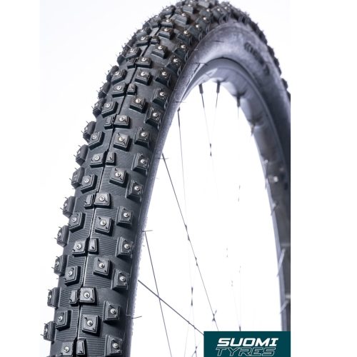 Närbild av ett cykeldäck med metalldubbar på slitbanan. Däcket är monterat på ett hjul med synliga ekrar. Logotypen "SUOMI TYRES" syns i det nedre högra hörnet.