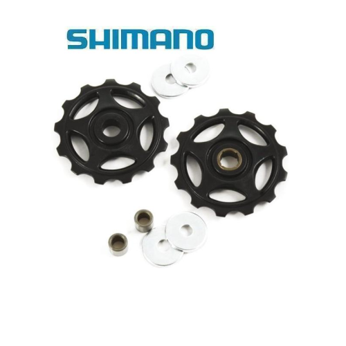 Två svarta Shimano cykelväxelhjul med fyra metallbrickor och fyra cylindriska bussningar mot en vit bakgrund. Den blå Shimano-logotypen visas ovanför komponenterna.