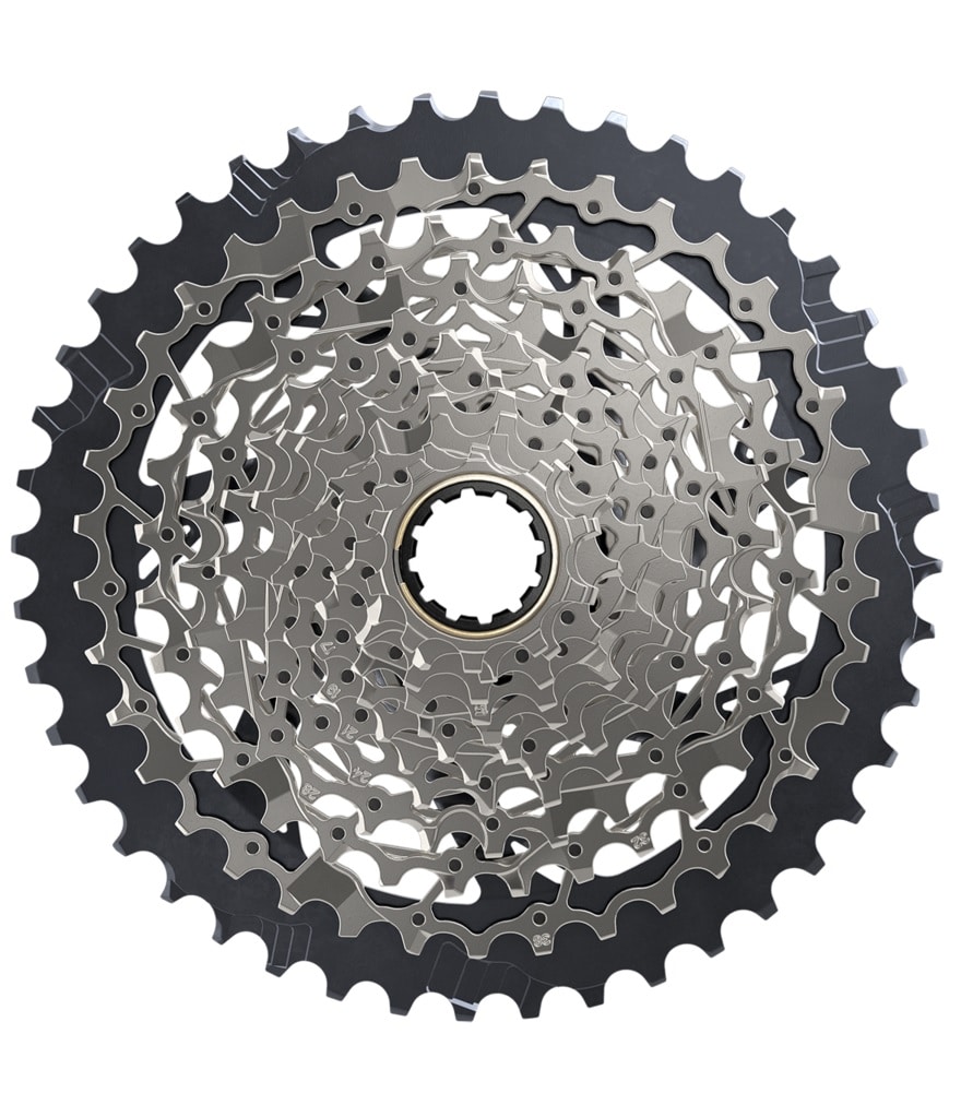 XPLR-1271-10-44-Kassett.jpg Närbild av en cykelkassett av metall med flera kugghjul i ett cirkulärt mönster, med intrikata utskärningar och kuggar av varierande storlek.