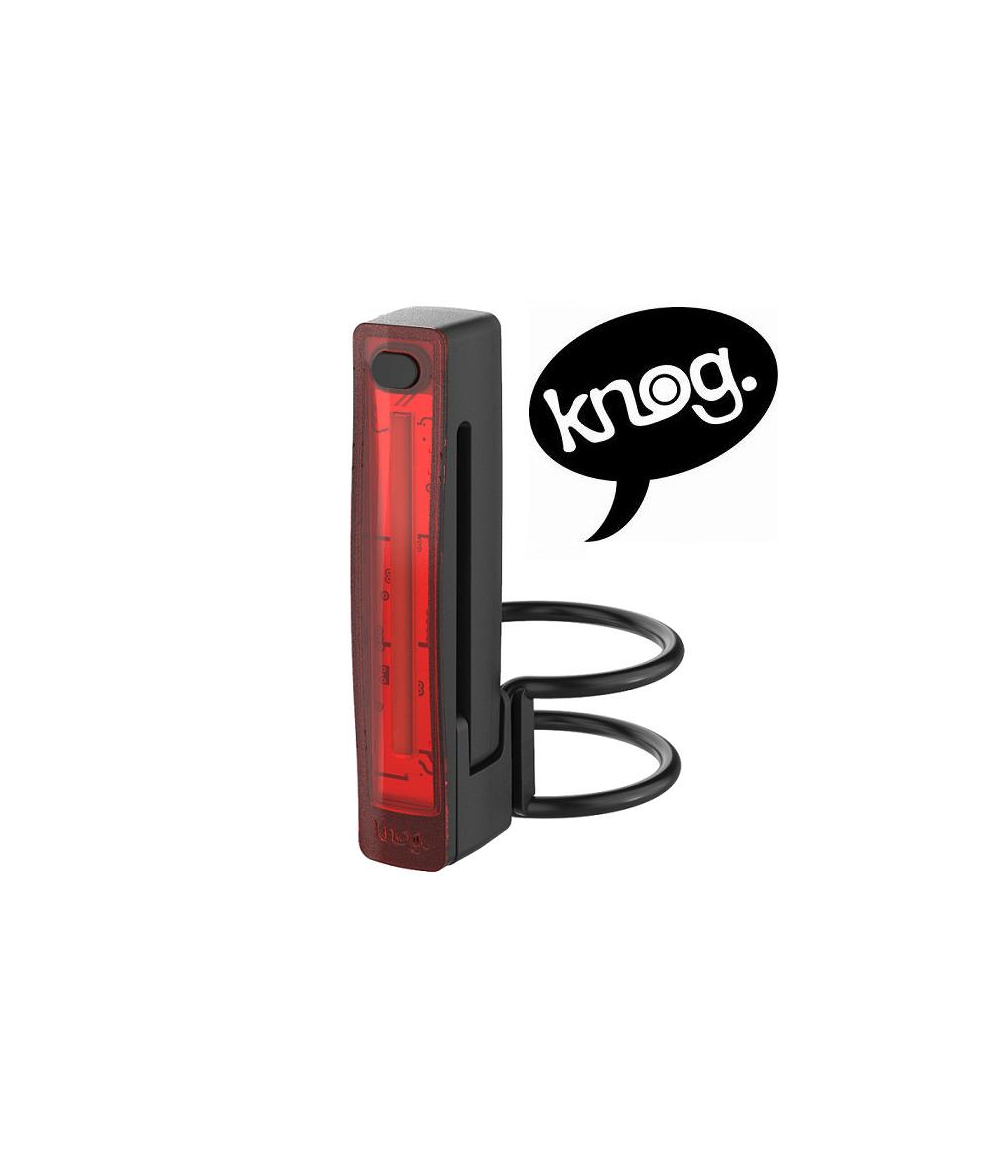baklampa-knog-plus.png En rektangulär röd och svart baklykta för cykel med ett monteringsfäste visas bredvid en pratbubbla med ordet "knog." i gemena bokstäver. Bakgrunden är vit.