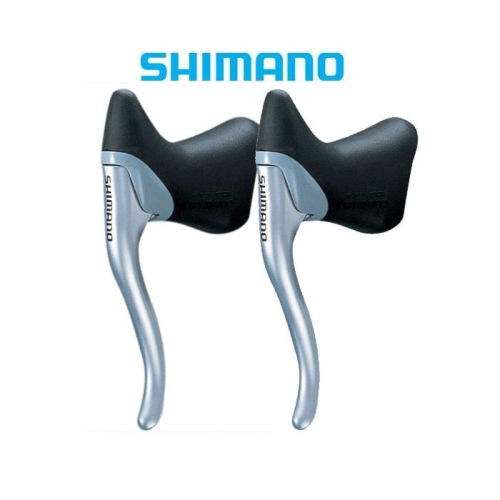 Två silverfärgade Shimano-bromshandtag för cykel med svarta kåpor visas sida vid sida mot en vit bakgrund. Shimanos logotyp visas ovanför spakarna i blå text.