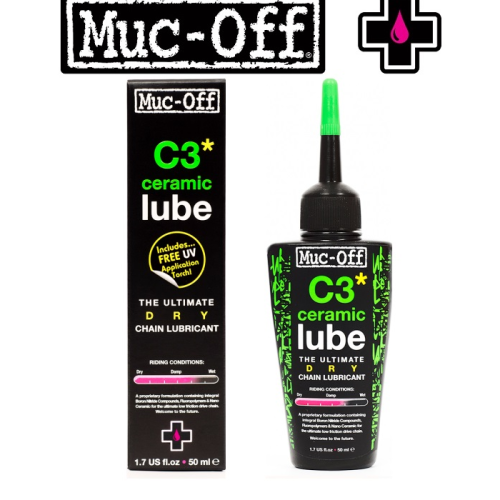 En flaska och en låda med Muc-Off C3 Ceramic Lube, ett torrt kedjesmörjmedel, visas. Flaskan har ett grönt munstycke och en svart etikett med gröna accenter. Lådan står upprätt med produktinformationen synlig.