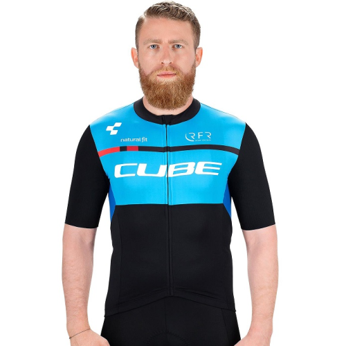 En man med rödbrunt skägg står vänd framåt, iklädd en svartblå cykeltröja med "CUBE" skrivet över bröstet och korta ärmar. Bakgrunden är enfärgad och vit.