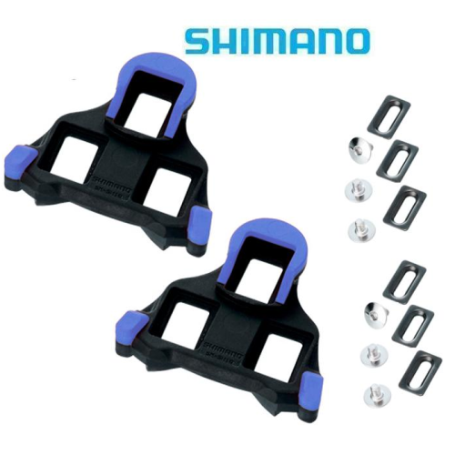 Ett par Shimano SPD-SL blå landsvägscykelklossar med hårdvara, inklusive bultar och metallplattor, på en vit bakgrund med Shimanos logotyp högst upp.
