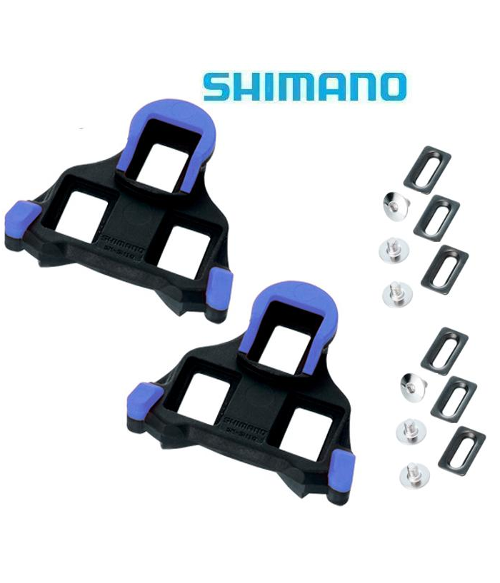 shimano-gulbla-kloss.png Ett par Shimano SPD-SL blå landsvägscykelklossar med hårdvara, inklusive bultar och metallplattor, på en vit bakgrund med Shimanos logotyp högst upp.