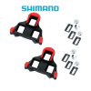 Två Shimano SPD-SL röd-svarta klossar för landsvägscyklar med tillbehör, inklusive skruvar och rektangulära brickor, visas på en vit bakgrund med Shimano-logotypen ovanför.