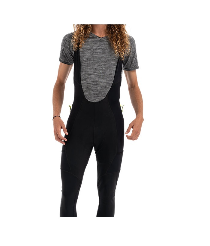 specialized-therminal-mountin-bib-knicker-whit-swat.png En person med långt lockigt hår bär en kortärmad grå skjorta och svarta cykeltights med haklapp. Huvudet är delvis utanför bild och bakgrunden är vit.