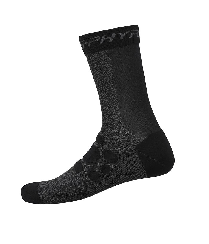 sphyre-sock-svartsvart.jpg En svart och mörkgrå sportstrumpa med texturerat mönster, förstärkt häl och tå samt varumärkesmärke runt den övre manschetten, på en vit bakgrund.