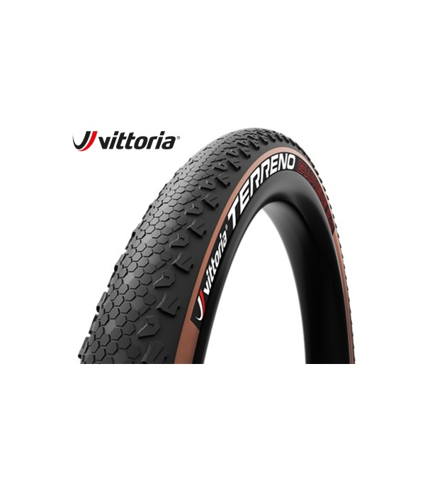vittoria-terreno.png En närbild av ett Vittoria Terreno cykeldäck visar ett strukturerat slitbanemönster och en brun sidovägg. Vittoria-logotypen visas i det övre vänstra hörnet på en vit bakgrund.
