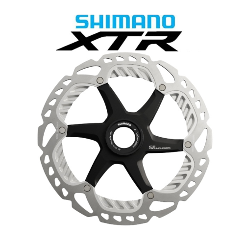 En Shimano XTR-cykelskivbromsrotor med silverfärgad och svart design visas under den blå och svarta Shimano XTR-logotypen på en vit bakgrund.