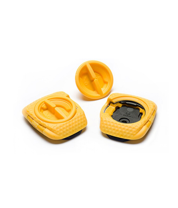 zero-pedal.png Tre gula plastföremål med strukturerade kanter visas mot en vit bakgrund. Två är fyrkantiga med cirkulära, roterbara centrum, och ett är en matchande rund bit som är separerad från en fyrkantig bas.