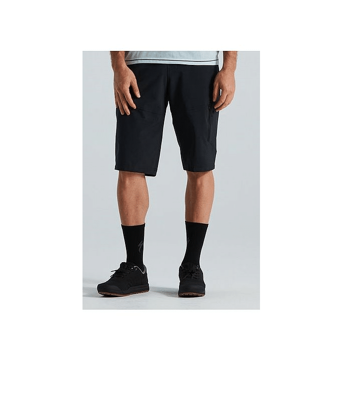 64221-6603.png Endast den nedre halvan av en person är synlig, klädd i svarta Specialized Trail Cargo Shorts, en ljusgrå skjorta, svarta strumpor och svarta sportskor mot en vanlig ljus bakgrund.