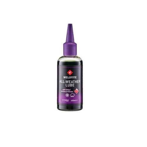 En flaska Weldtite All-Weather Lube kedjeolja, 100 ml, med mörklila kork, mot en neutral bakgrund. Etiketten betonar produktens lämplighet för alla väder.