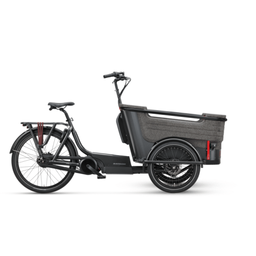 En svart eldriven trehjulig lastcykel med en stor, grå lastlåda framtill, två framhjul, ett bakhjul, upprätt styre och ett lastställ baktill, visad i profil mot en vit bakgrund.