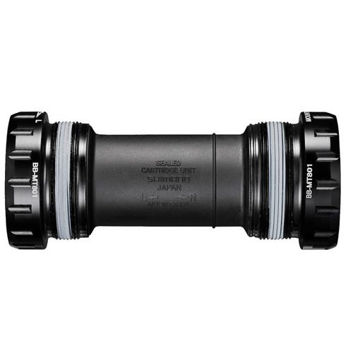 Ett detaljerat fotografi av ett Shimano XT BB-MT800 vevlager, BSA 68/73 mm. Vackert ljus framhäver vevlagerets svarta färg, med betoning på Shimano-logotypen och produktmärkningen.