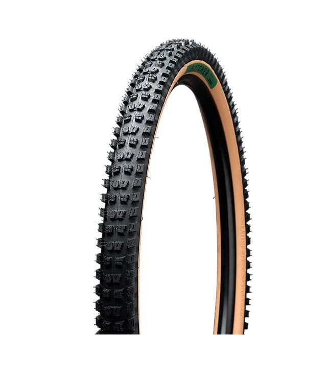 BUTCHER-GRID-TRAIL-2BR-T9-TIRE-SOIL.jpg Detaljerat foto av ett Specialized Butcher Grid Trail MTB-däck med beige sidovägg och kraftigt mönster, presenterat i studioljus mot en vit bakgrund.