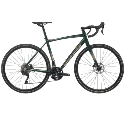 En grön Bianchi cykel med silverfärgade detaljer står i studioljus. Cykeln har bockstyre, skivbromsar och däck med mönster för både landsväg och terräng.