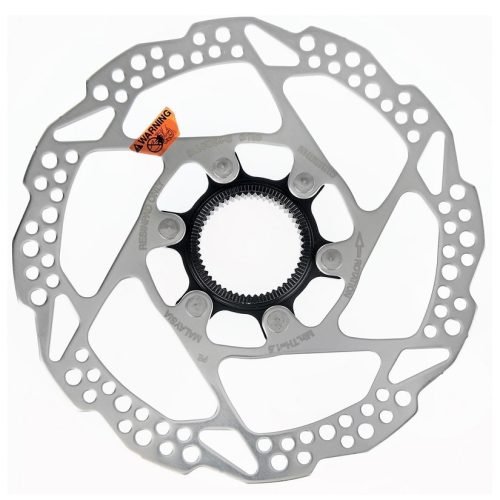 Närbild av en Shimano Alivio SM-RT54S bromsskiva för cykel med centerlock-infästning. Skivan är silvrig med hålmönster och en orange varningsetikett. Ljuset är jämnt och framhäver detaljerna.