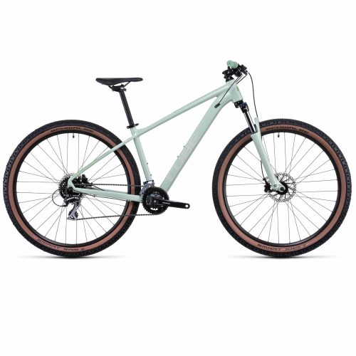 En mintgrön mountainbike med svart sadel, svart styre och breda däck med solbruna sidoväggar, i profil mot en vit bakgrund.