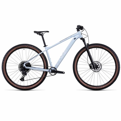 En profilvy av MTB 27,5" Cube Acid - Vit, en ljusgrå hardtail mountainbike med framgaffel med fjädring, platt styre, skivbromsar och knobbydäck med bruna sidoväggar mot en vit bakgrund.