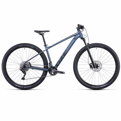 MTB Cube Attention 27,5" 2x11s i grå/blå har en lättviktsram, platt styre, framgaffel med fjädring, skivbromsar och knobbydäck, sedd från sidan mot en vit bakgrund.