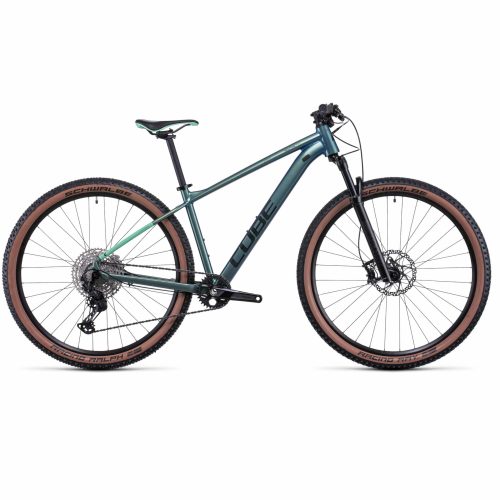 MTB 29" Cube Reaction Pro 29" har en metallgrön ram, svart styre, brunmönstrade däck, framfjädring, skivbromsar och "CUBE"-märke på ramen. Visas mot en enfärgad vit bakgrund.