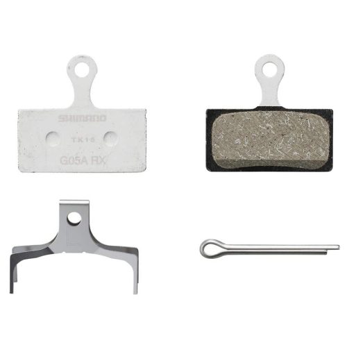 Närbild av Shimano G05A resin skivbromsbelägg. Beläggen, fjädern och sprinten visas mot en ren, vit bakgrund med en lätt skugga som förstärker detaljerna.