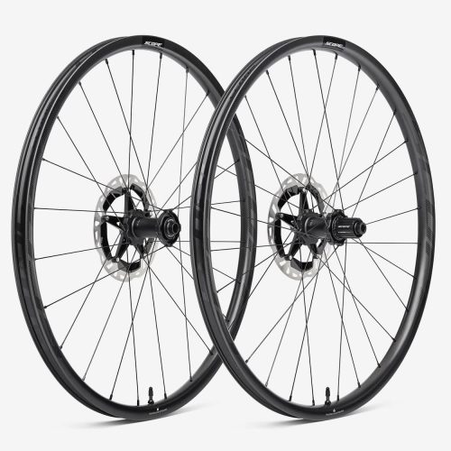 Två landsvägscykelhjul från Scope, avbildade i en studio mot en vit bakgrund. Hjulen har kolfiberfälgar och skivbromsar, med subtil branding och minimal belysning som framhäver deras aerodynamiska design.
