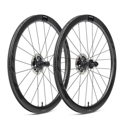 Två Scope R4.A 45 mm hjulpar för racer cyklar. Stark belysning framhäver kolfiberstrukturen och det aerodynamiska djupet. Skivbromsar framträder tydligt.