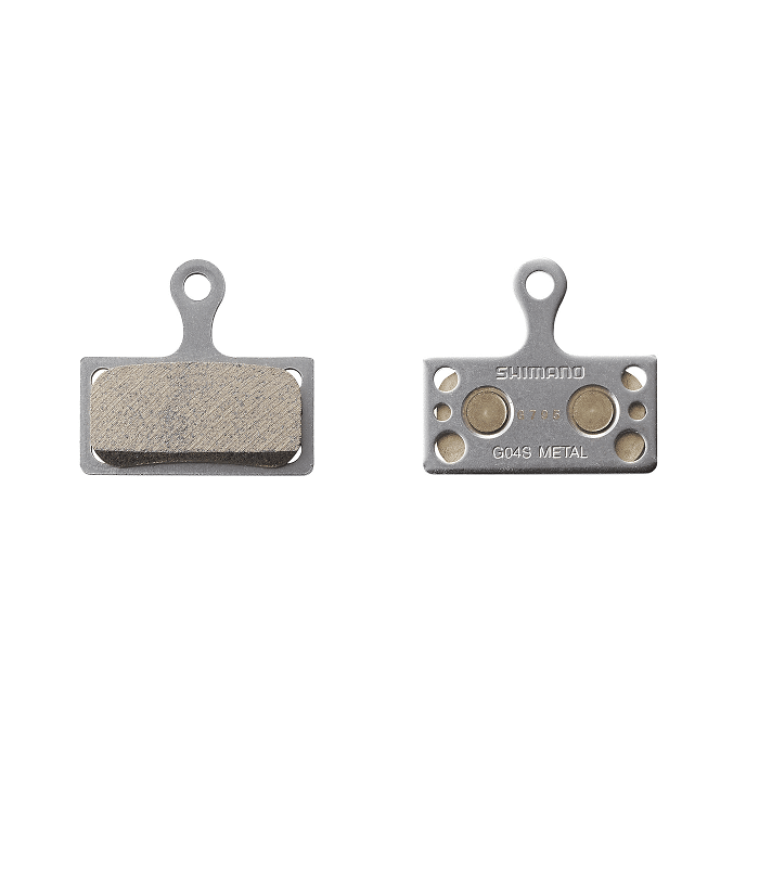 IBPG04SMXA.png Två Shimano XT G04S skivbromsbelägg i metall visas mot en vit bakgrund. Den vänstra belägget visar bromsytan, medan den högra visar metallbaksidan med "SHIMANO" och "G04S METAL" tryckt.
