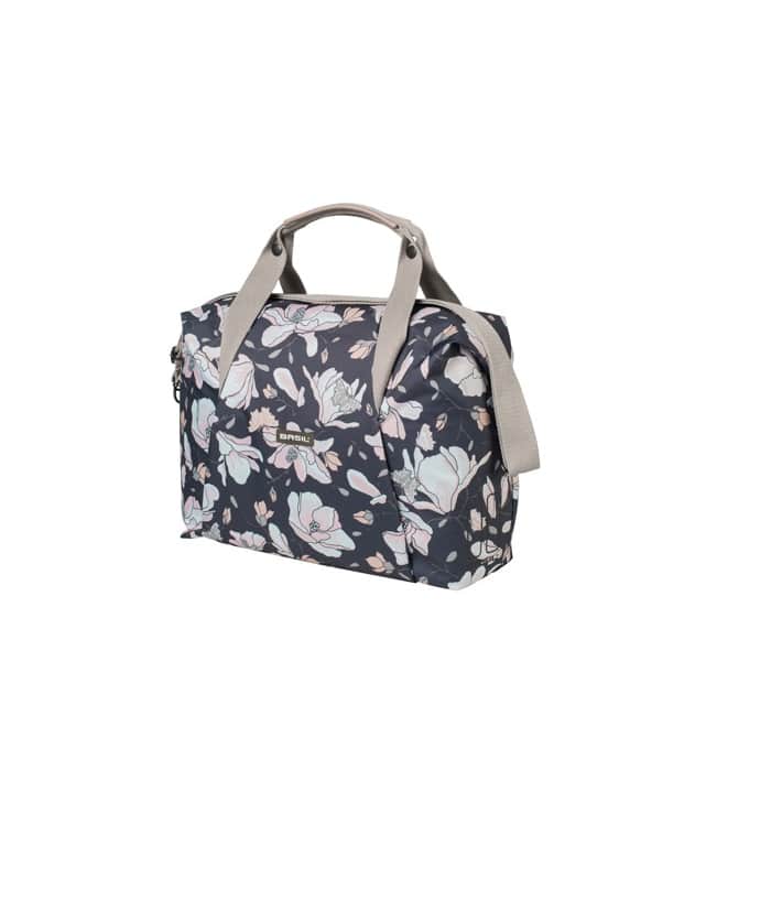 Magnolia.jpg Cykelväska Basil Magnolia 18 liter är en rektangulär handväska med beige handtag och axelrem, med en mörk bakgrund med ljusrosa, vitt och blått blommönster.