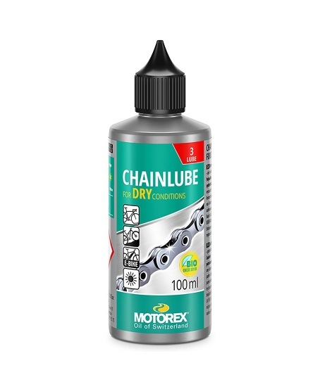 Motorex-CHAINLUBE-DRY-CON-100ml Flaschen med Motorex kedjeolja för torra förhållanden framträder med etikett i gröna och silverfärgade nyanser, detaljerad kedjeillustration och svart pipkork. Den rena bakgrunden förstärker produktens fokus.