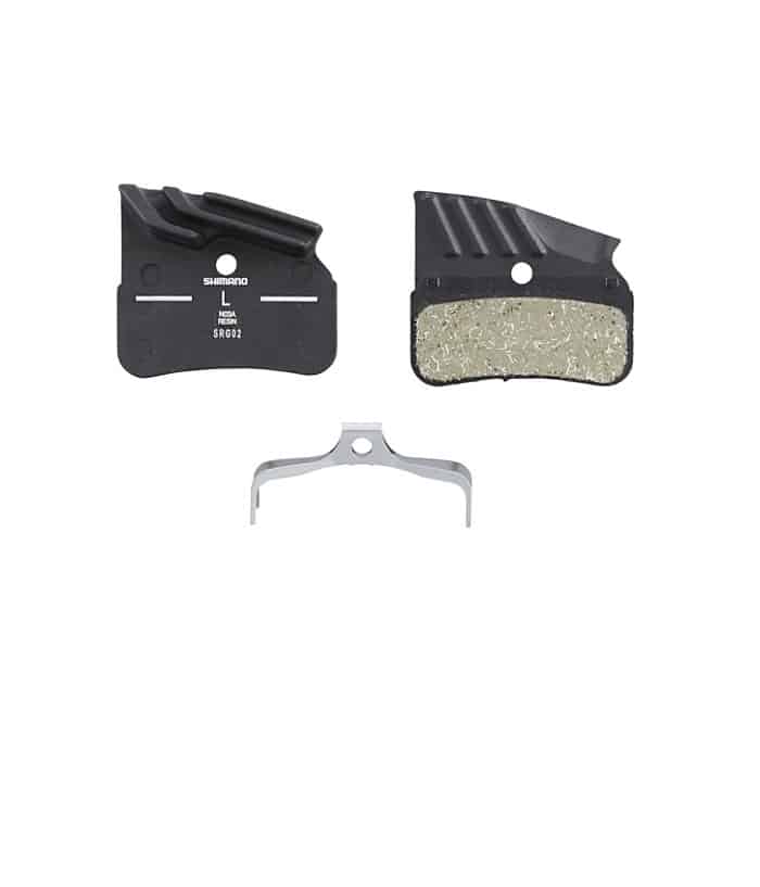 N03A.jpg Detaljerad bild av Shimano N03A Resin skivbromsbelägg, presenterade mot en ren, vit bakgrund. Den skarpa belysningen framhäver texturerna och formen hos beläggen och fjädern.