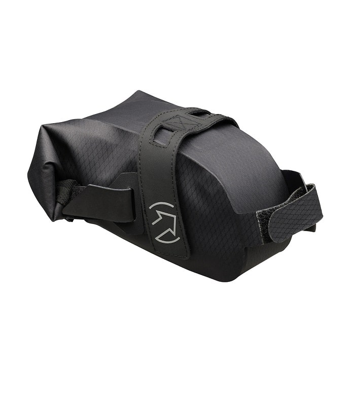 PRBA0068.jpg Sadelväska Gravel Team Saddle Bag är en kompakt, svart rektangulär cykelväska med en strukturerad yta, fäst med kardborreband och med en vit pil-logotyp på sidan. Slitstark och perfekt för gruscykling.