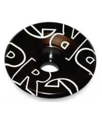 Topcap PRO 1 1/8 Aluminium är en svart, platt, cirkelformad aluminiumbit med ett centralt hål och vit stiliserad text på ytan.