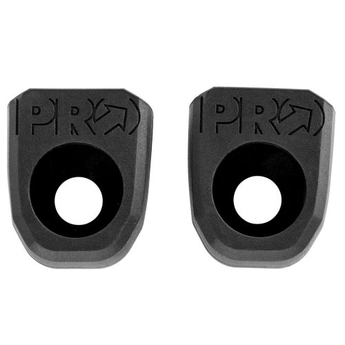 Närbild av två svarta Pro Crank Protectors på vit bakgrund. Skydden är av gummi med ett runt hål i mitten och "PRO" ingraverat upptill. Jämn belysning.