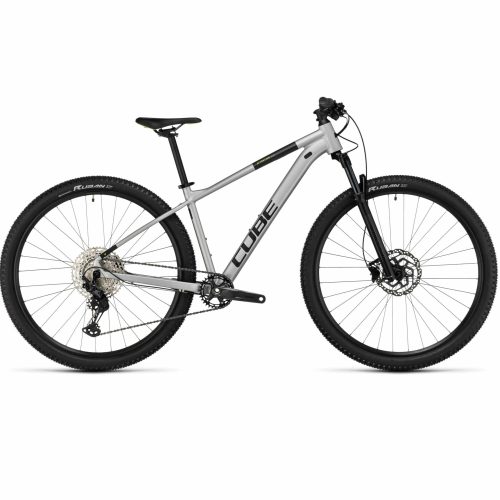 En silverfärgad Cube mountainbike med svart styre, hjul och sadel, med framfjädring, skivbromsar och "CUBE"-märke på ramen, fotograferad från sidan mot en vit bakgrund.