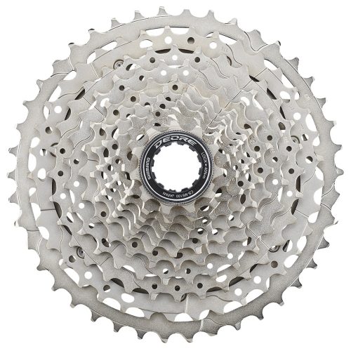 Detaljerad bild av en silverfärgad Shimano Deore CS-M5100 11-växlad kassett, centrerad och belyst, visar tydligt taggarna och detaljerna runt låsmuttern märkt 'Shimano DEORE'.