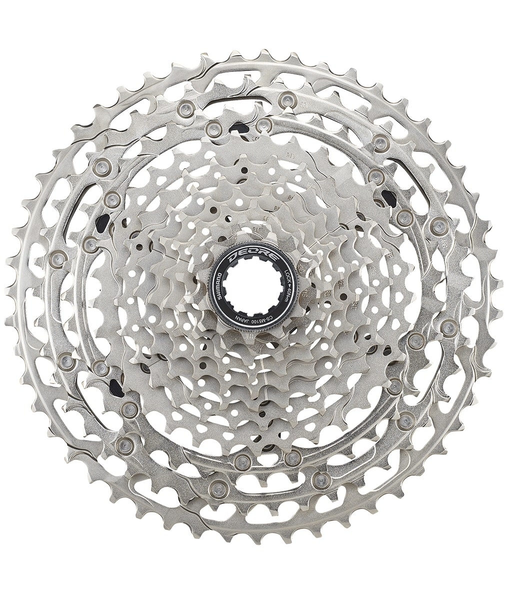 Shimano-Deore-11-51.jpg Silverfärgad Shimano Deore CS-M5100 11-växlad kassett, fotograferad i starkt ljus mot en vit bakgrund. Detaljerade kuggar och texten på låsringen är väl synliga.