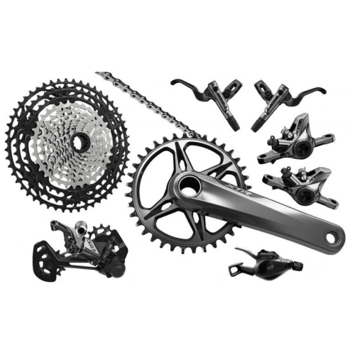 Shimano XTR M9100 grupp i silver och svart, med detaljerade komponenter som kassett, kedja, vevparti, bromsar och växelreglage i studioljus.