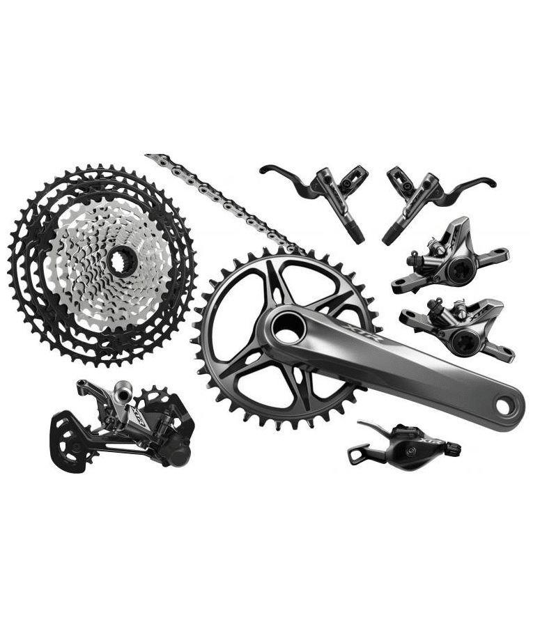 Shimano-xtr-m9100-grupp.png Shimano XTR M9100 grupp i silver och svart, med detaljerade komponenter som kassett, kedja, vevparti, bromsar och växelreglage i studioljus.