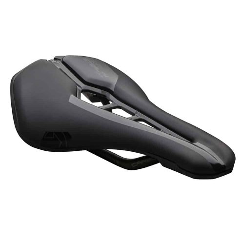 Detaljrik produktbild av en svart Pro Stealth Curved Team cykelsadel i dämpad belysning. Sadlen har en distinkt, ergonomisk form och synliga kolfiberdetaljer, presenterad mot en neutral bakgrund.