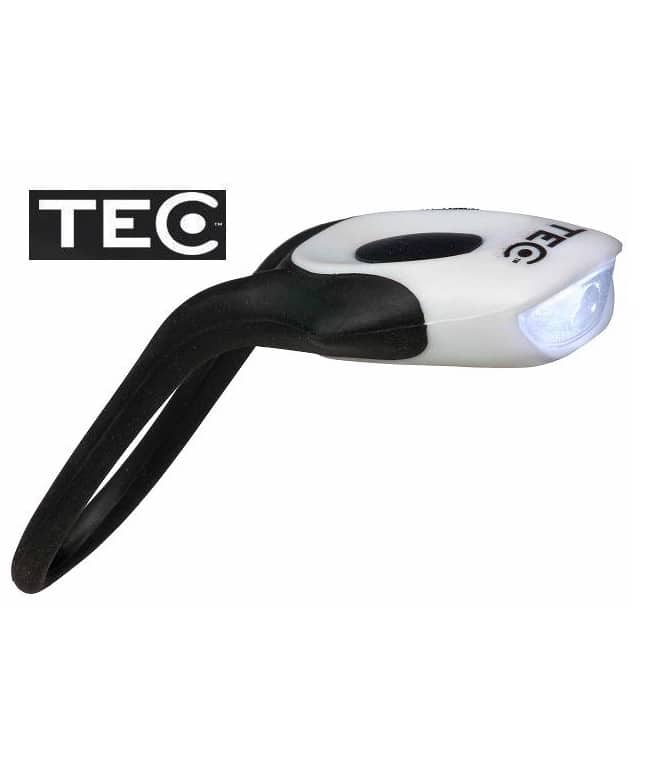 Tec-Rana-Framlampa.jpg En kompakt, vit och svart Framlampa Tec Rana 1-lysdiod LED-lampa med en flexibel fästögla visas upplyst, med TEC-logotypen synlig i bakgrunden.