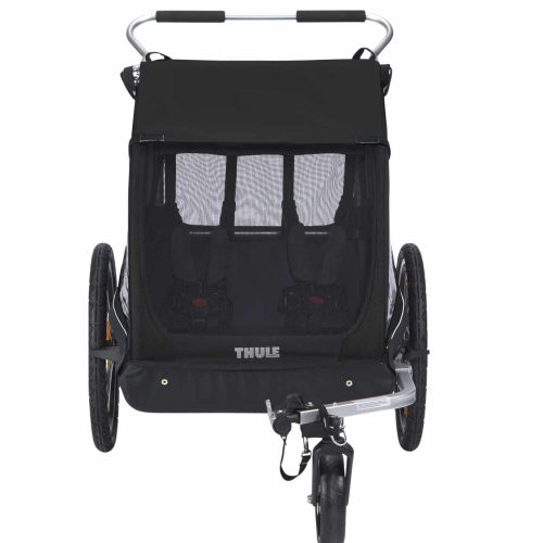 En vy framifrån av den svarta Cykelvagn Thule Coaster XT för 2 barn, med två säten, en nätfrontpanel, stora sidohjul och ett bakre styre. Utformad för säker och bekväm transport av barn.