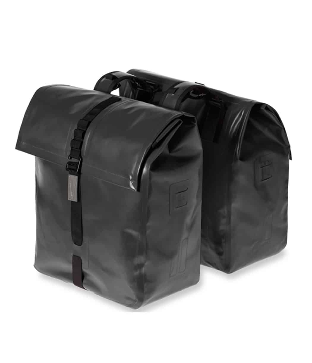 UrbanDry-Double-Bag-50L-Black.jpg Två svarta, rektangulära Cykelväska Basil Urban Dry Double Bag packväskor (50L) med rullstängning och svarta spännband, stående sida vid sida mot en vit bakgrund.