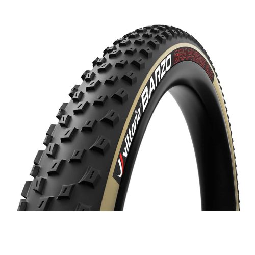 Närbild av ett Vittoria Barzo MTB-däck med tan-sidovägg och svarta knoppar, framhävt i starkt ljus som betonar dess detaljer och mönster. Texten "Vittoria Barzo" är tydligt synlig.