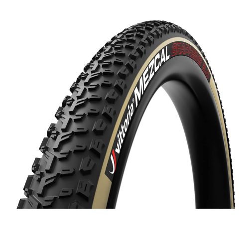 Detaljerat foto av ett Vittoria Mezcal 29" MTB-däck med tan sidovägg och svarta däckmönster, tydligt belyst för att framhäva dess struktur och design.